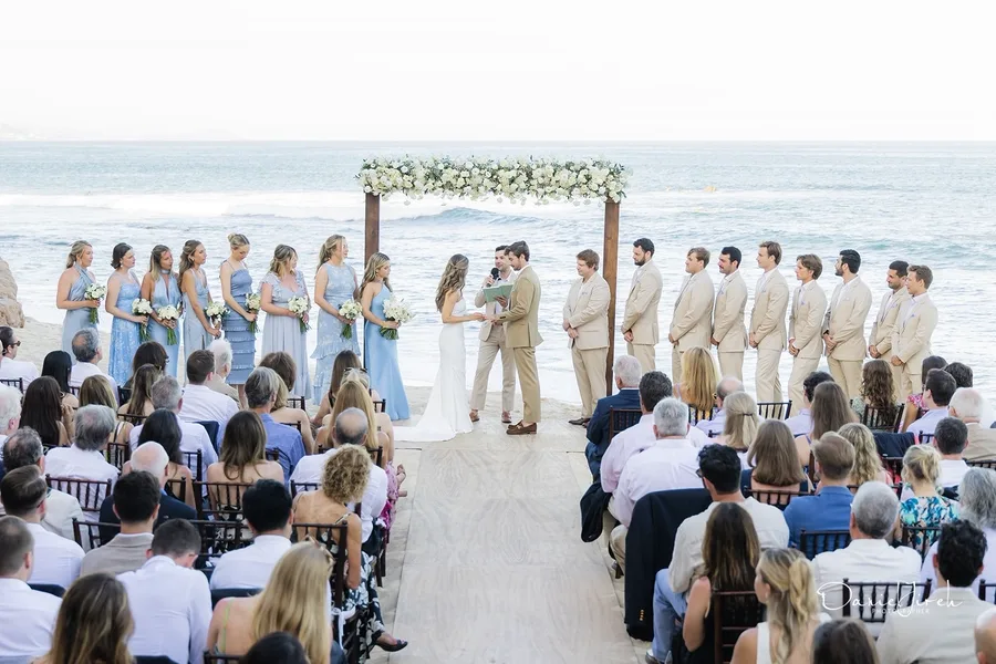 Bride and groom exchanging vows with bridesmaids in blue